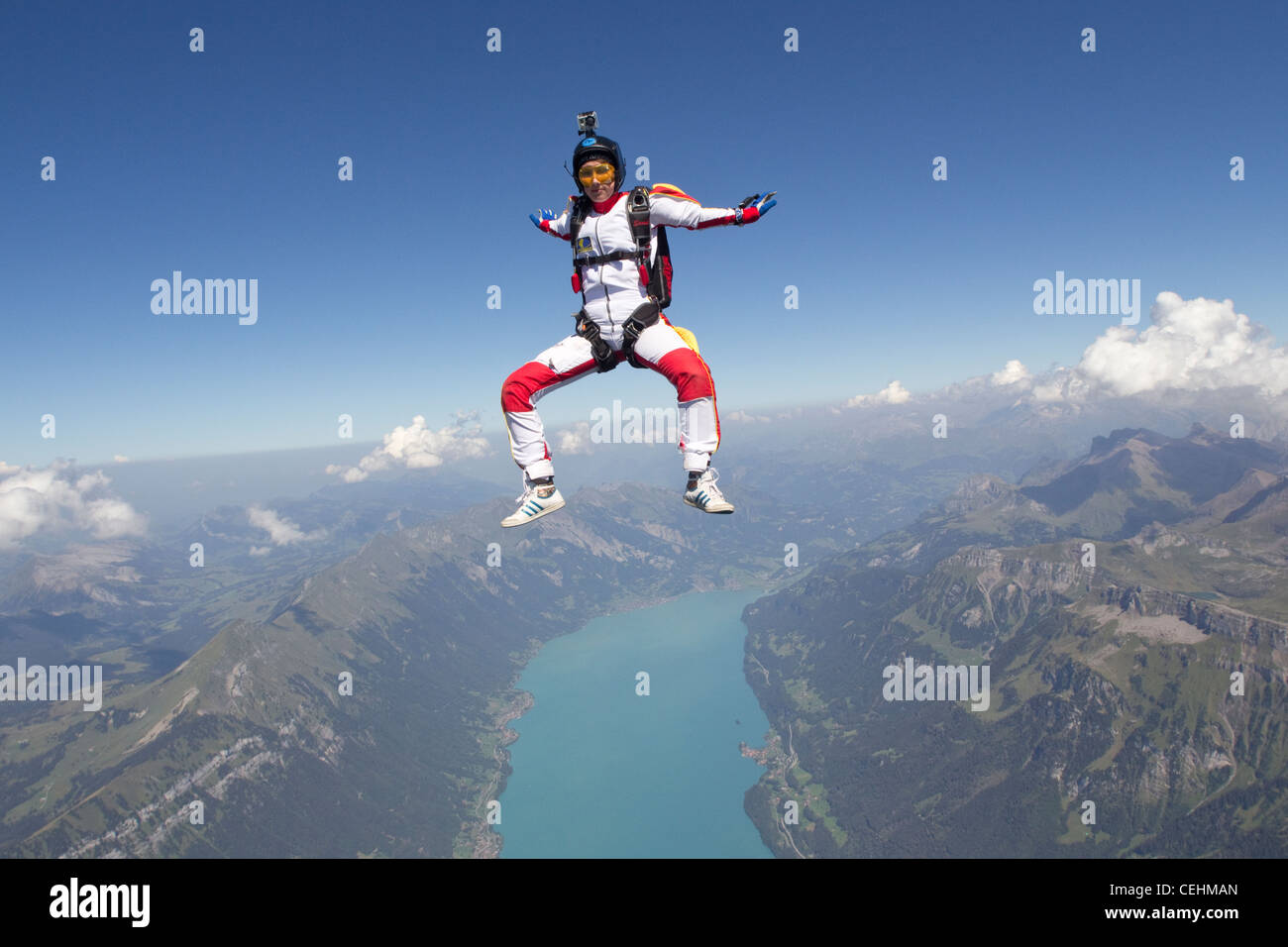 Skydiver girl is practice the sit position and flying free over a lake and nice mountain scenery with over 120 MPH. Stock Photo