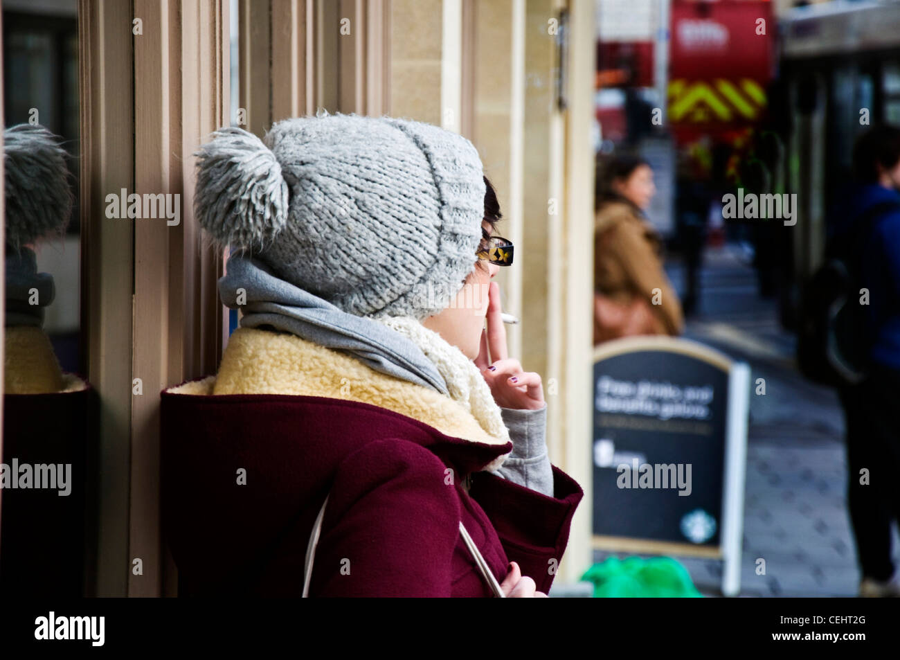 Young woman smoking at a bus stop Stock Photo