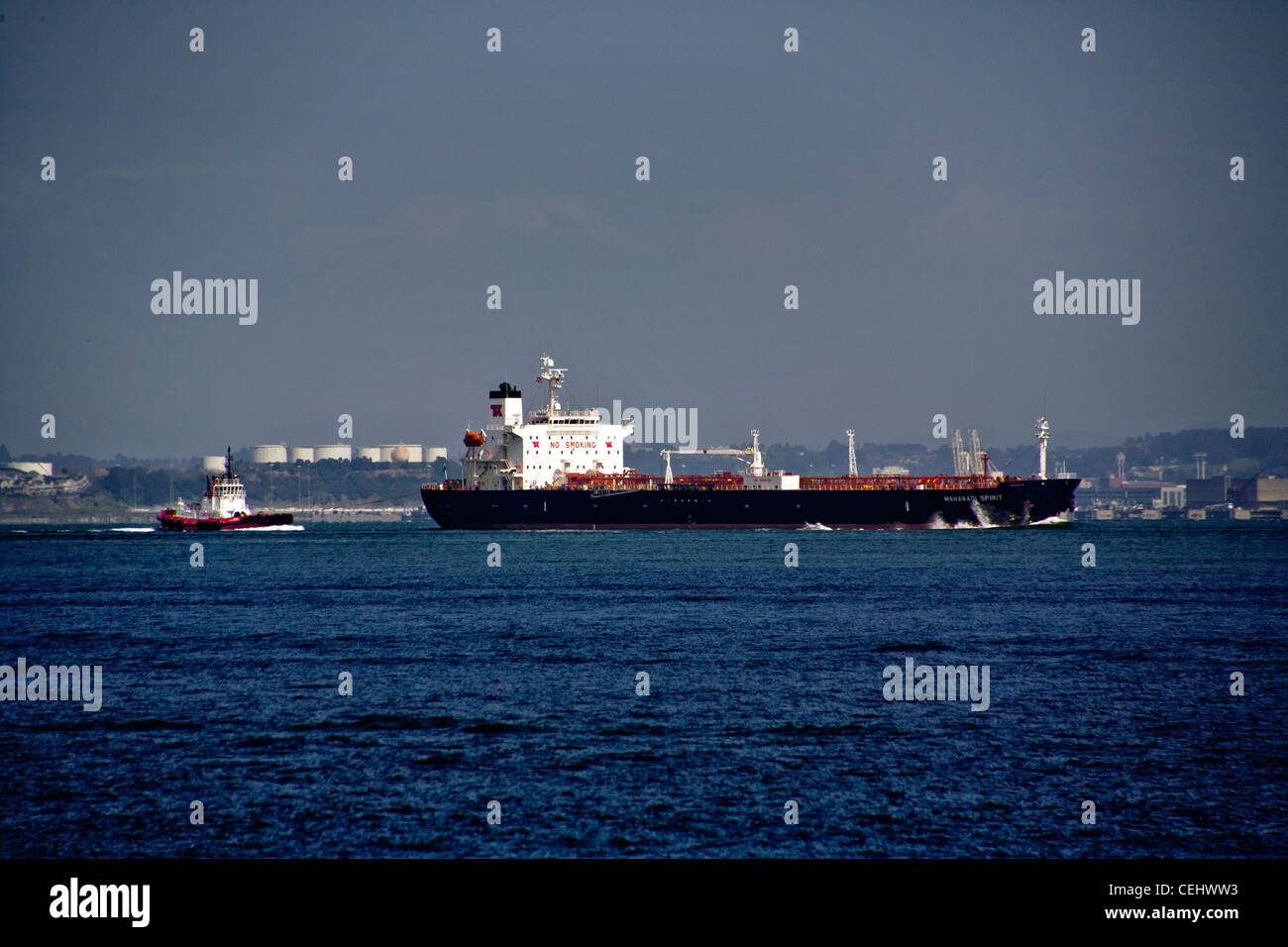 Accompanied by a tugboat, an ocean going oil tanker crosses San Francisco Bay. Note large 'No Smoking' sign on ship. Stock Photo