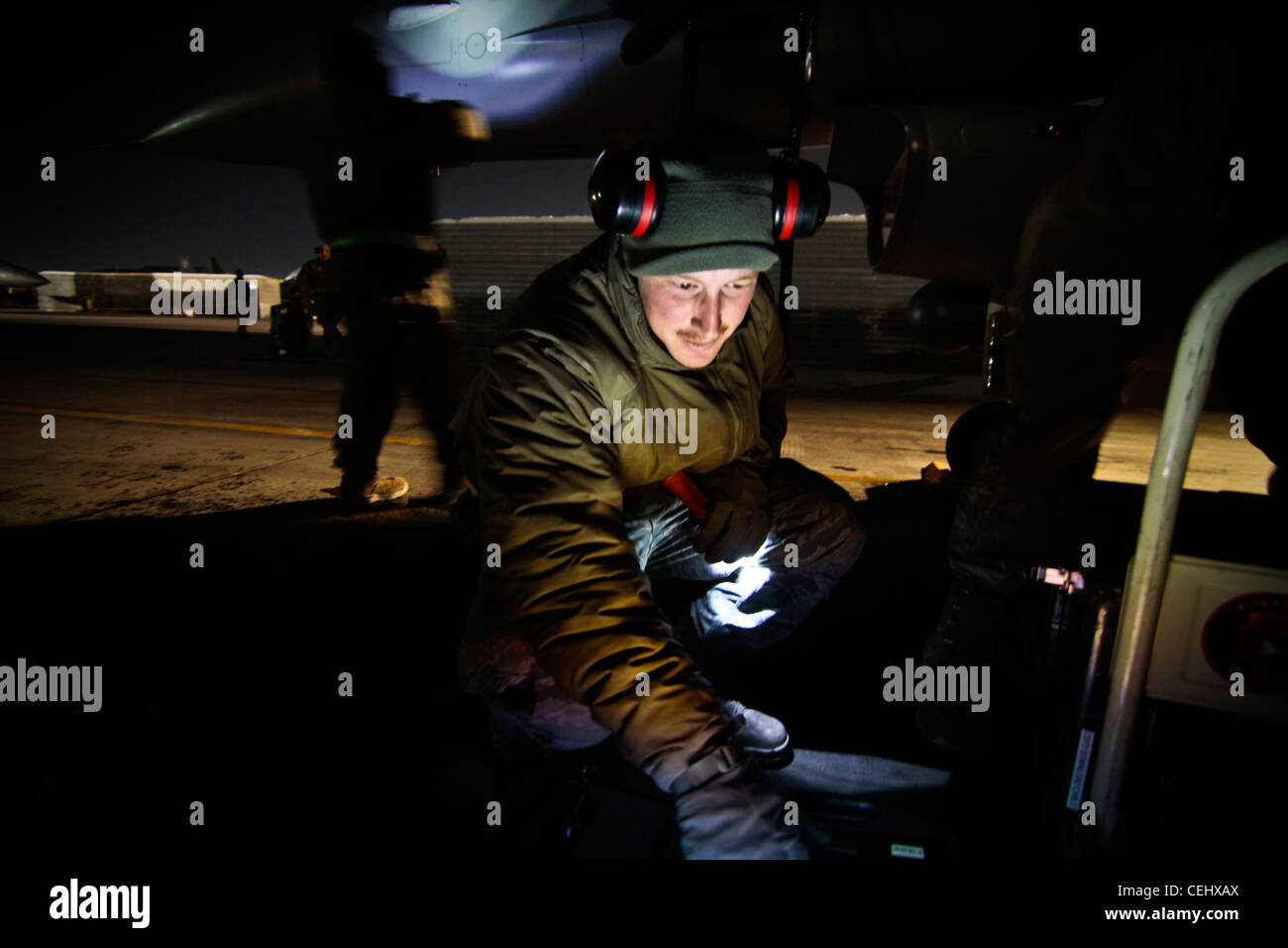 U.S. Air Force Tech. Sgt. Sean Latimer, an F-16C Fighting Falcon crew chief, performs maintenance on an aircraft on Feb 14, 2012. Latimer is assigned to the 455th Expeditionary Aircraft Maintenance Squadron, and is deployed from the 177th Fighter Wing, New Jersey Air National Guard. Stock Photo