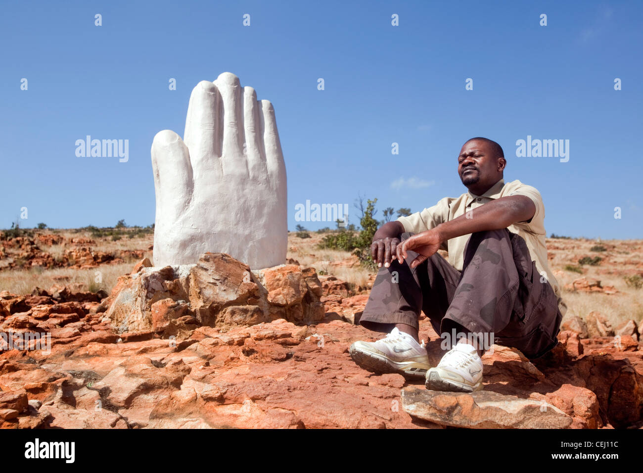 Man praying at Praying Hands Statue, Magaliesberg,North West Province Stock Photo