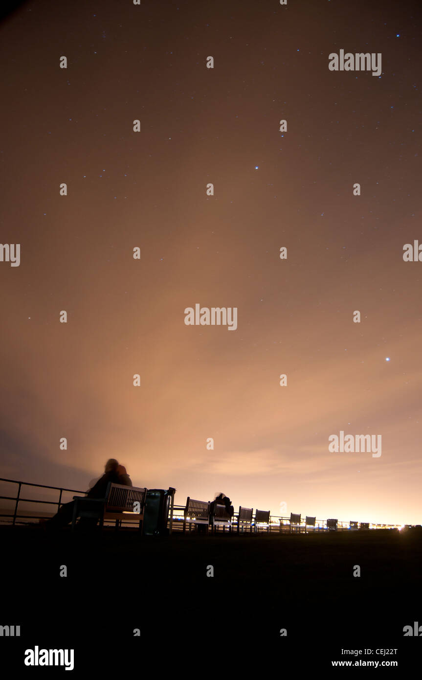 Benches facing the sea photographed at night Stock Photo