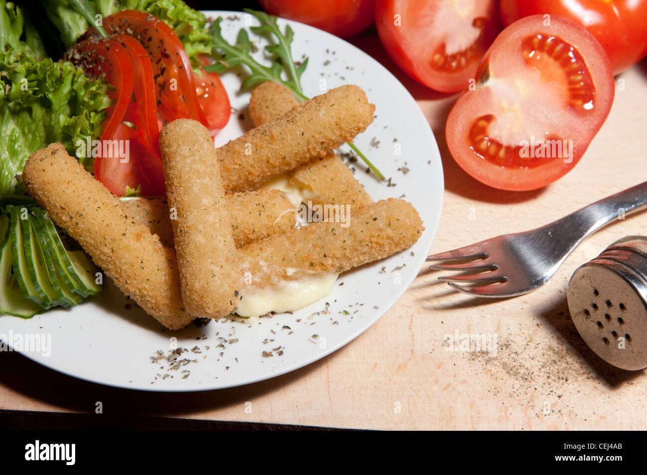 Breaded chilli peppers with cheese + salad (tomatoes, lettuce, cucumber). Stock Photo