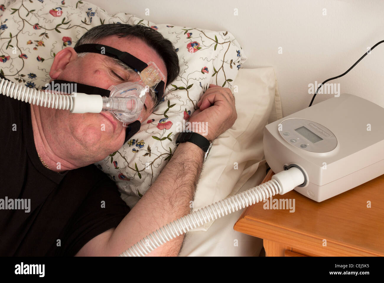 Man using a CPAP face mask and machine used for the treatment of sleep apnea. Stock Photo