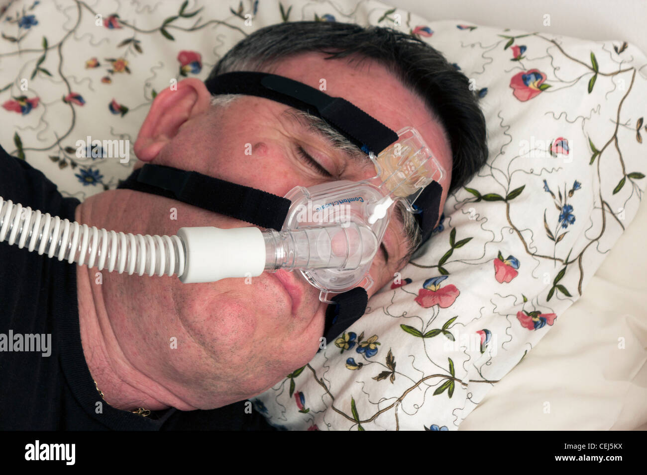 Man using a CPAP face mask and machine used for the treatment of sleep apnea. Stock Photo