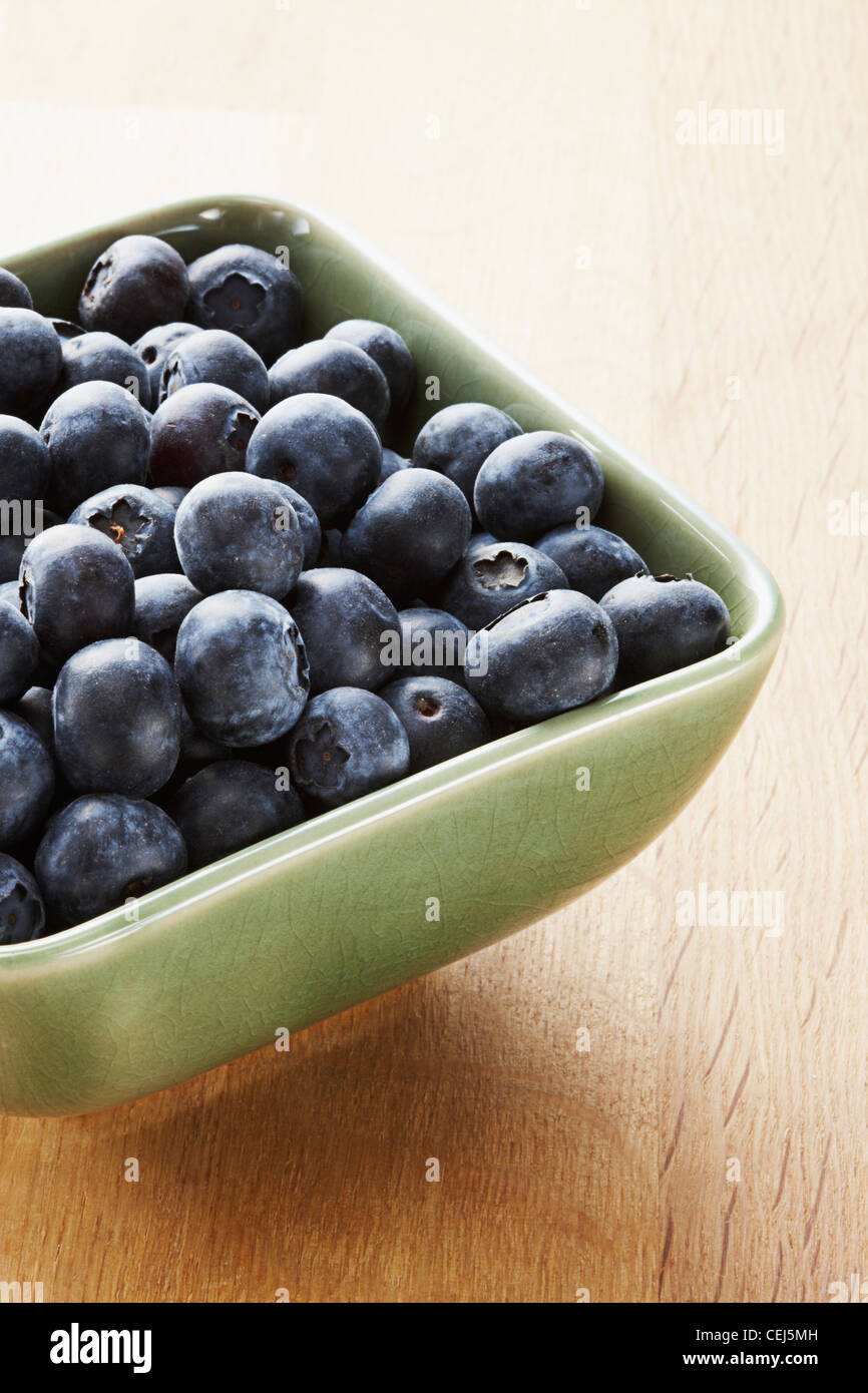 Blueberries in a green bowl on a wooden background Stock Photo