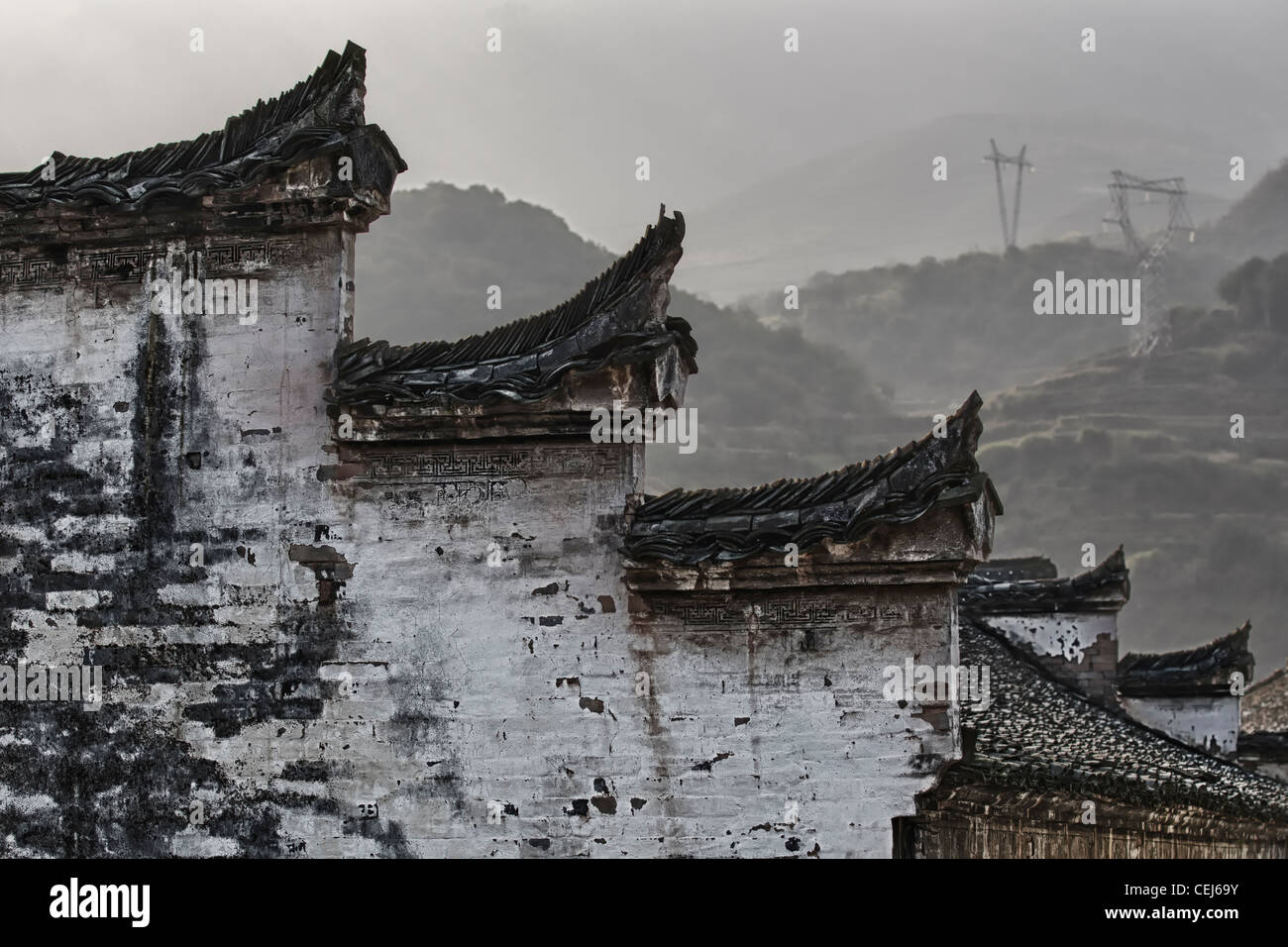 A Chinese hui style wall and roof shaped like horse heads and harmonized with black and white color, mountains in the background Stock Photo