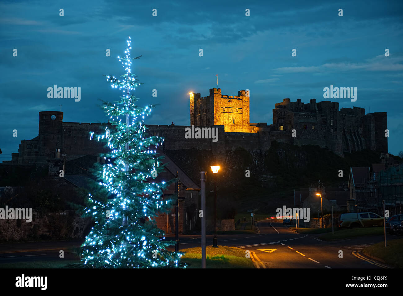 Bamburgh Castle, Northumberland, England, UK, from the West, at dusk, with a Christmas tree in the foreground Stock Photo