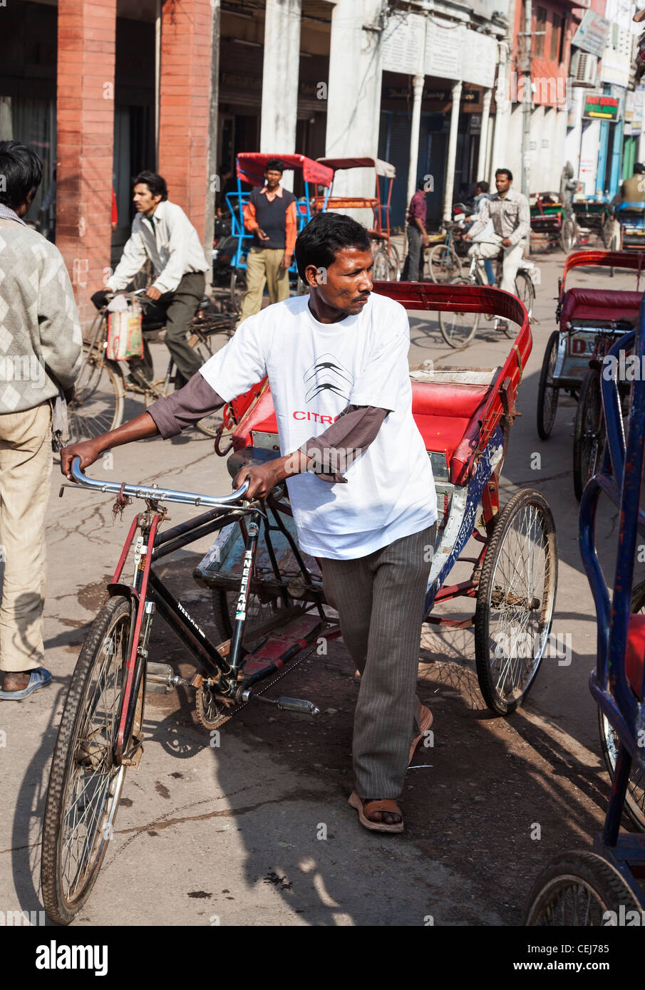 Street life in Old Delhi, India with bicycle rickshaw wallah in a crowded street in sunshine Stock Photo