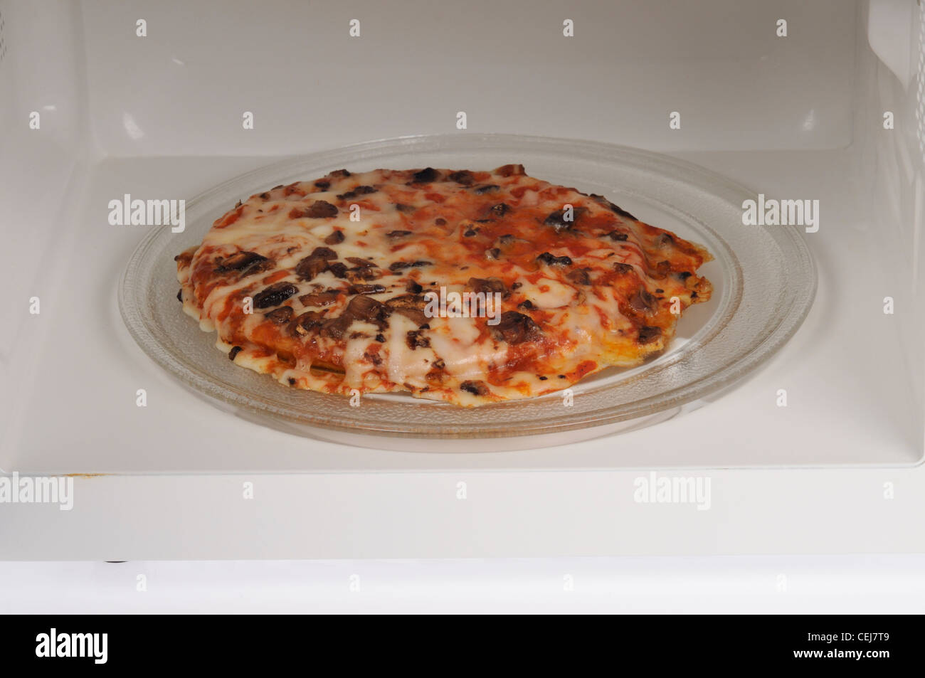 Cooked frozen mushroom pizza inside microwave oven Stock Photo