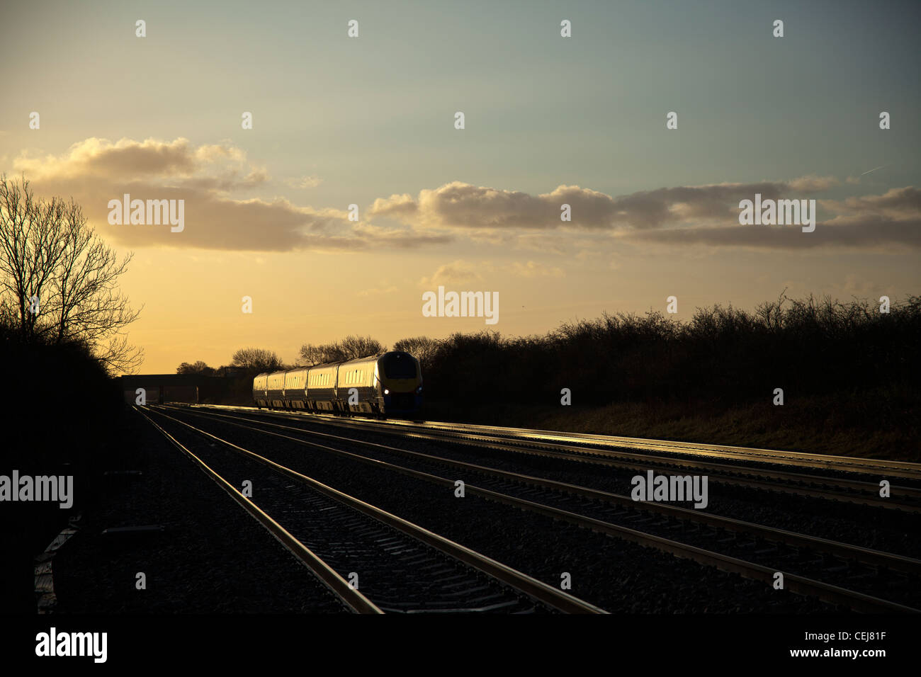 East Midlands Trains class 222 Meridian catches early morning glint sunlight at Cossington foot crossing. Stock Photo