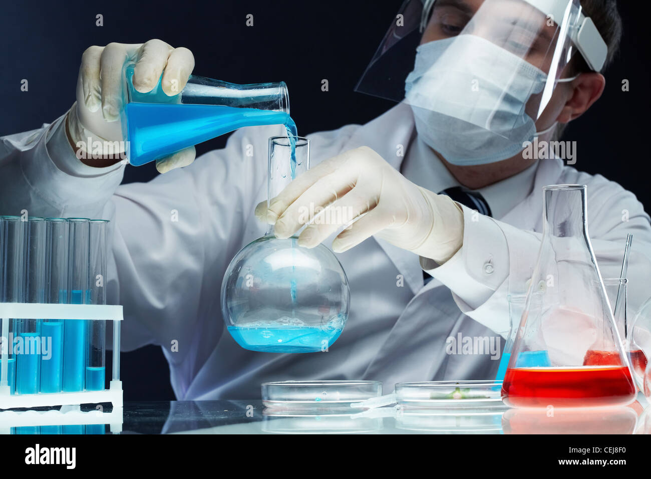 Scientist pouring fluid substances from one beaker into another Stock