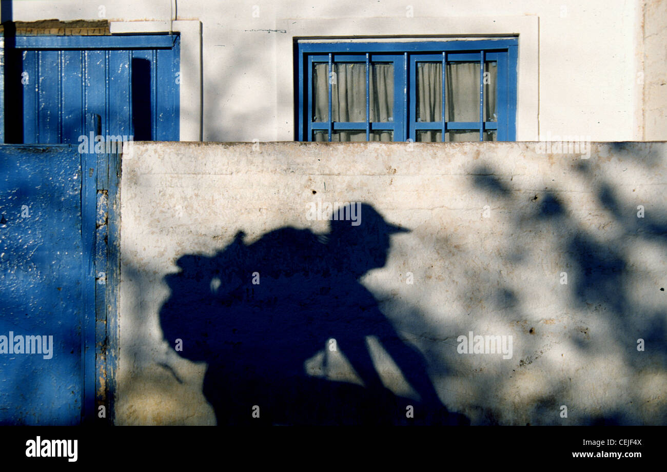 Shadow of a cyclist peddling through a village in northern Chile at sunset. Stock Photo