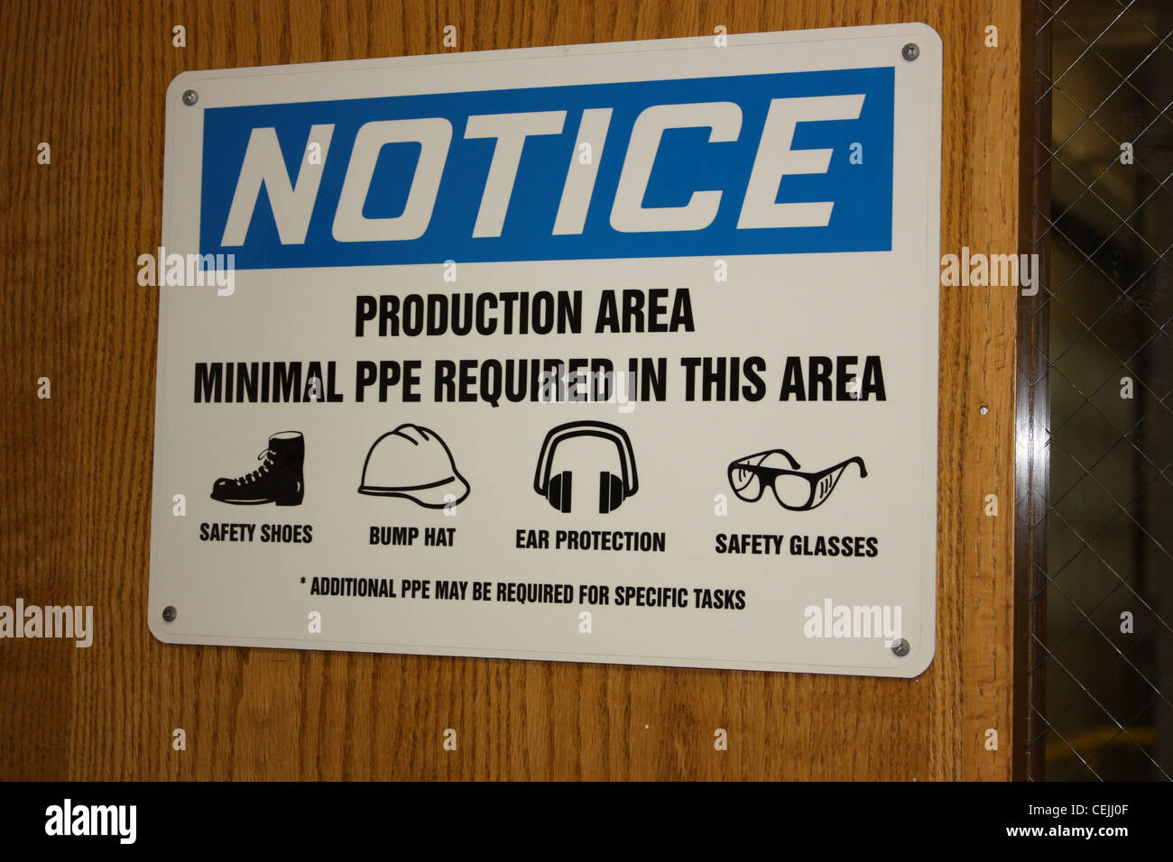Notice warning sign in a industrial work area with personal protection required in this area