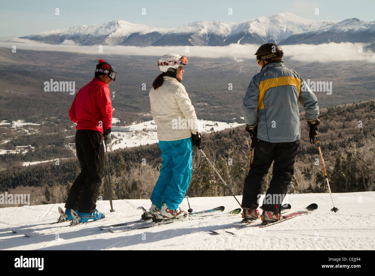 A trio of skiers stand at the top of Bretton Woods Ski area in NH, with the presidential Range in the background. Stock Photo