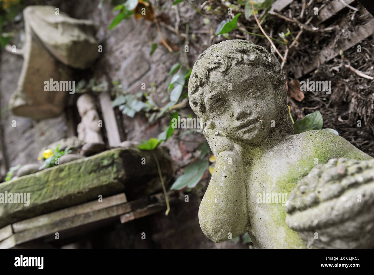 Hidden Treasure Child statue with garden feature on the wall in background Stock Photo