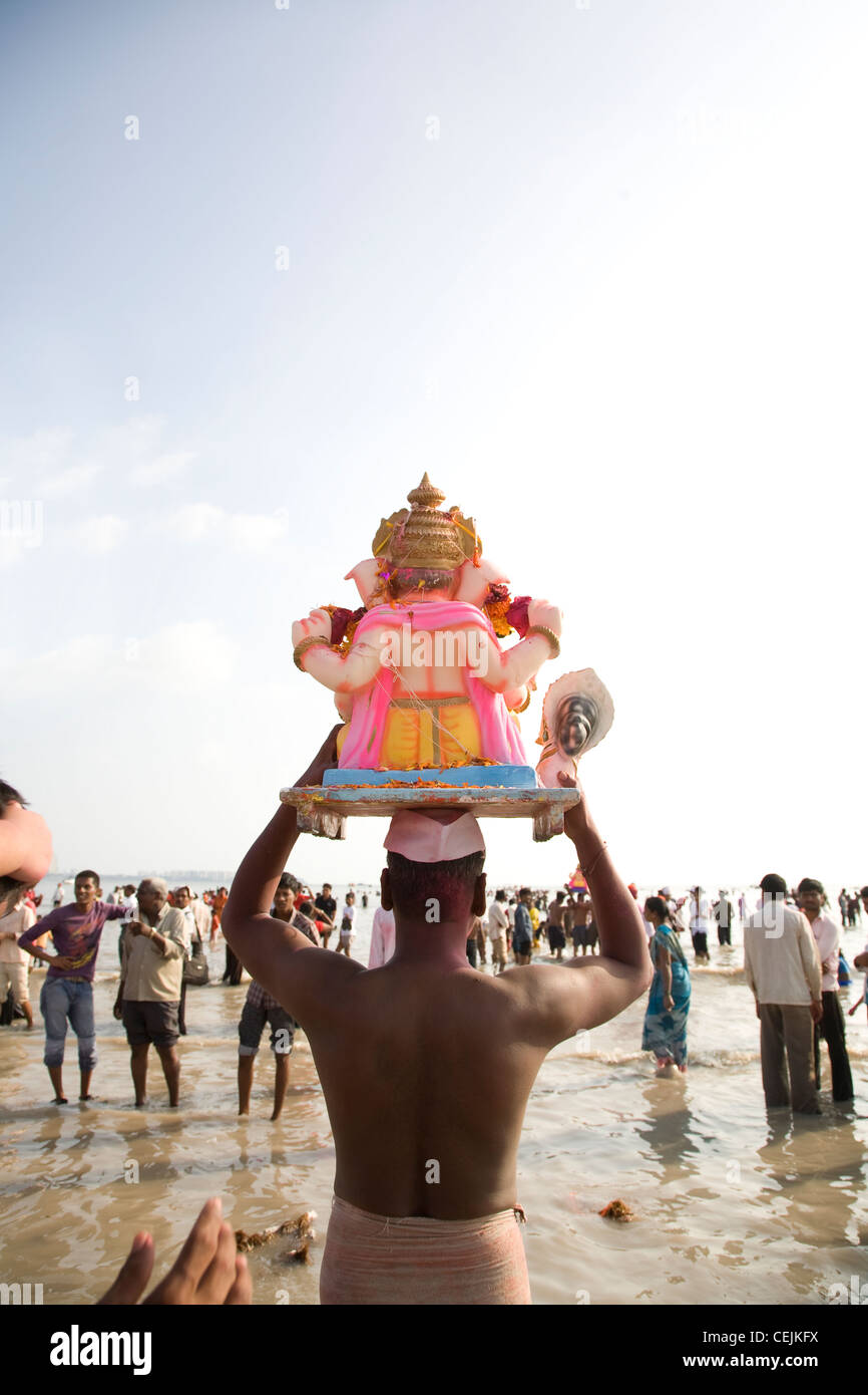 Believer carrying small Ganesh Idol for immersion - Scenes from Ganesha Visarjan in Mumbai Stock Photo