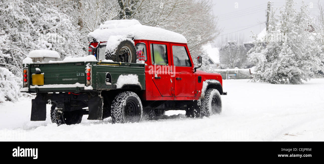 Snow scene Land Rover Defender 130 4x4 pickup driving on narrow country lane road in winter snowfall cold weather Brentwood Essex England UK Stock Photo