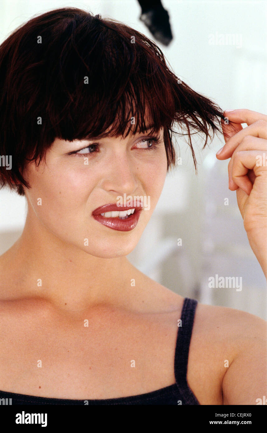 Brunette Female With Short Bob Abd Thick Fringe Pulling A Strand