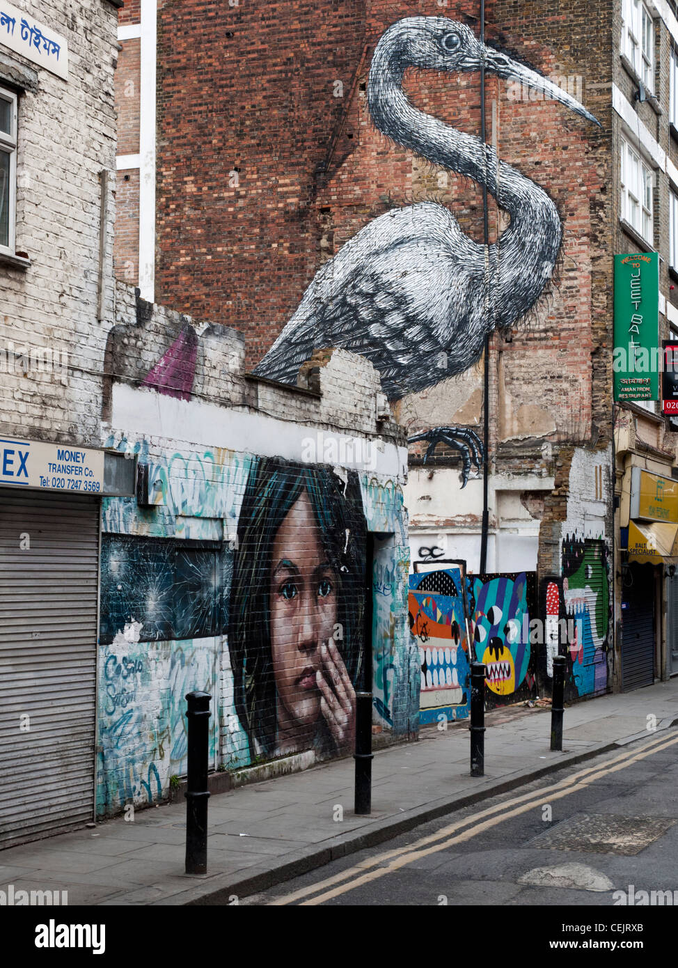 Street art of a bird by the artist Roa in Hanbury Street , East London. The artwork in the foreground is by artist Cosmo Sarson. Stock Photo