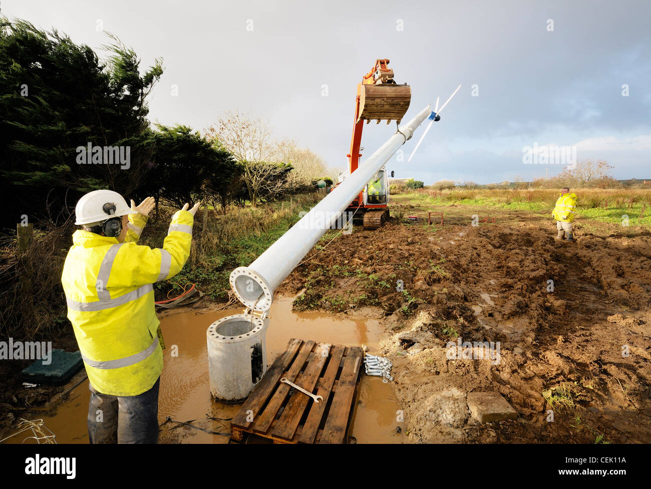 Engineers erecting household wind turbine for generating domestic electricity and feeding surplus into the UK national grid Stock Photo