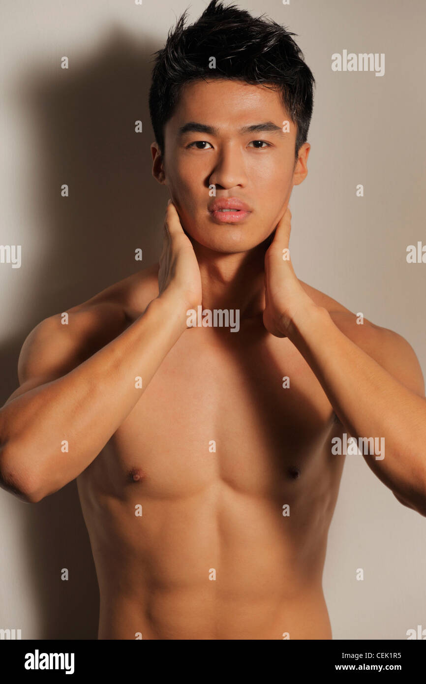 Shirtless young man with hands on neck Stock Photo - Alamy