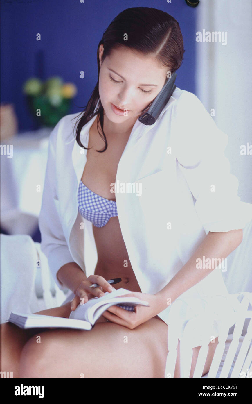 Female long wet brunette hair wearing blue and white gingham bra and knickers under open white blouse, sitting on chair Stock Photo