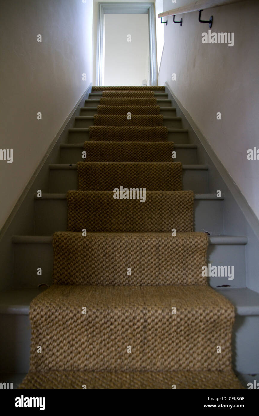 A rustic staircase with a sisal runner carpet in an oldfashioned