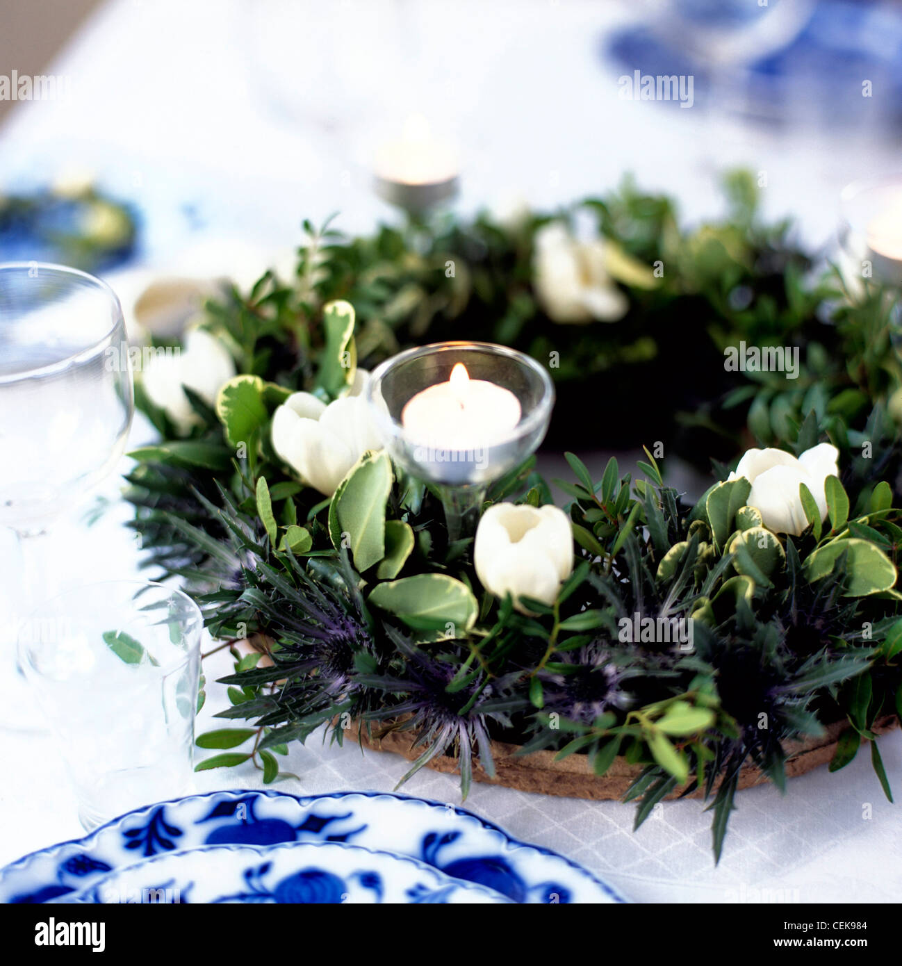 Table Art Very little is required to impress guests, a few green leaves, lit candles and crisp white flowers, small beautiful Stock Photo