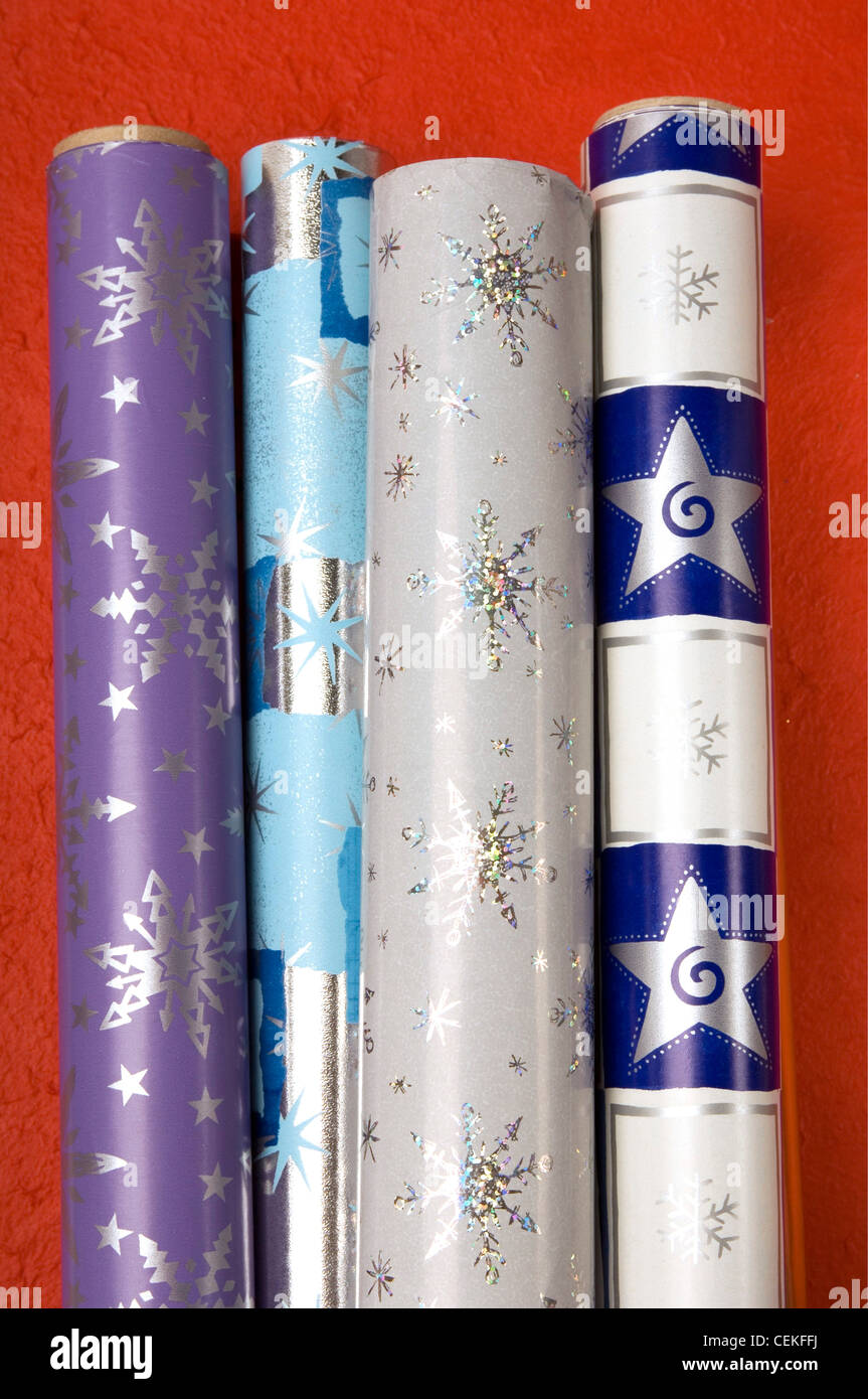 Close up of four rolls of patterned Christmas wrapping paper on a red background Stock Photo