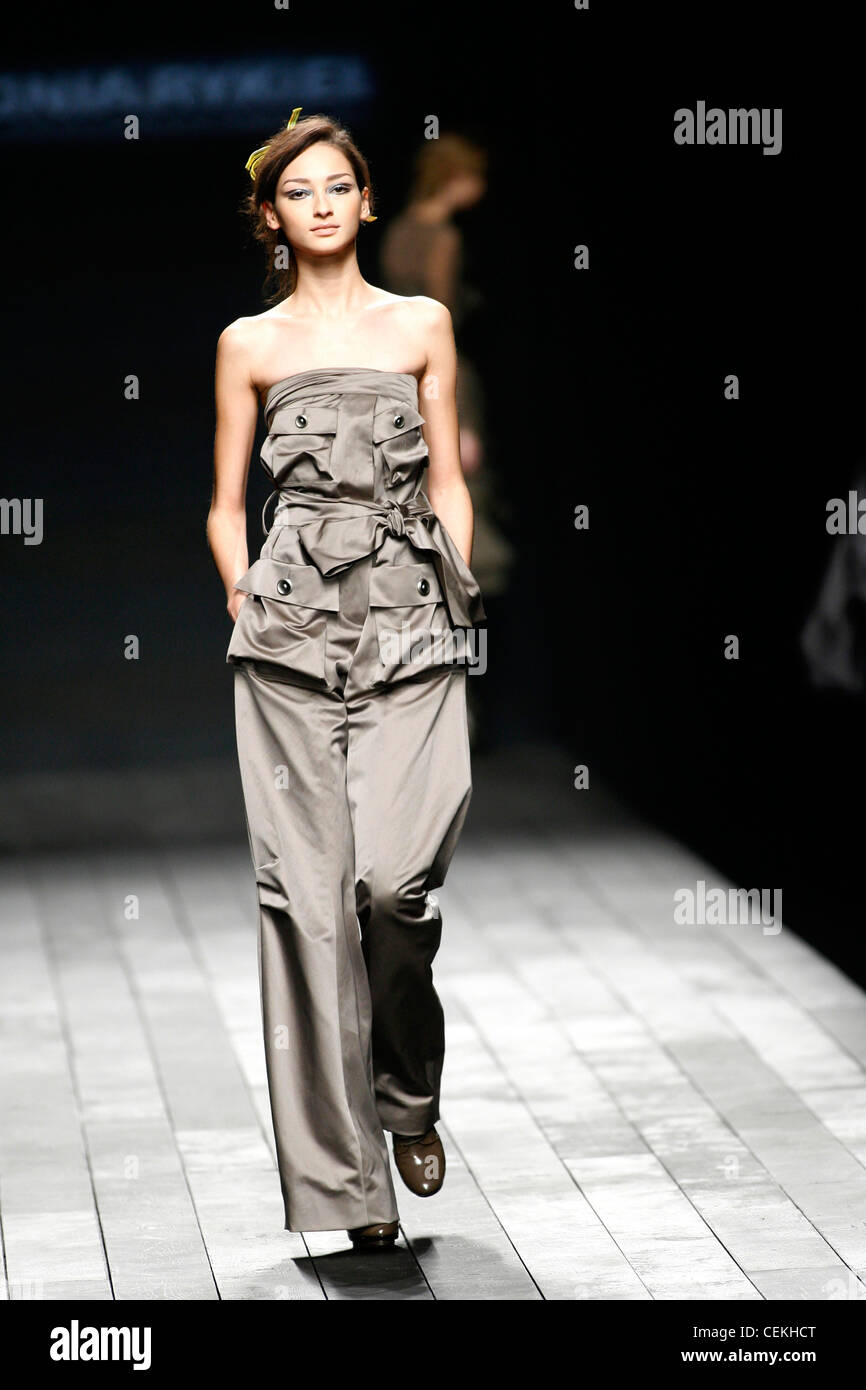Model wearing grey satin one piece strapless wide leg trouser jumpsuit with pockets Stock Photo
