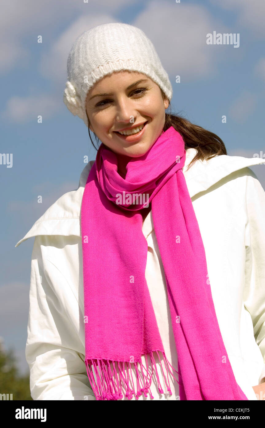 Female wearing white coat, cerise pink pashmina scarf and white wool hat  with flower corsage Stock Photo - Alamy