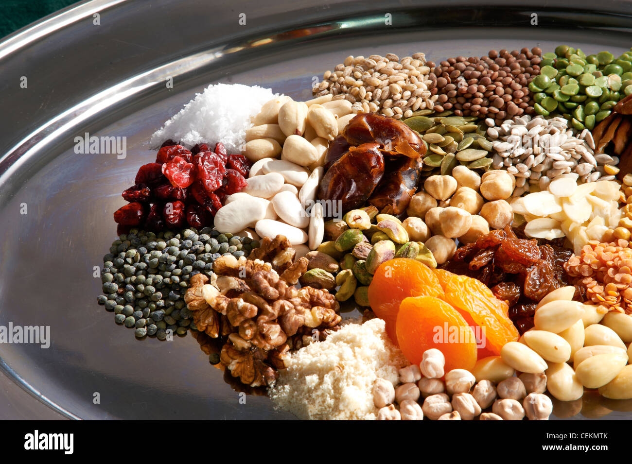 Close up of a colourful range of pulses, nuts, seeds and dried fruits on a silver oval tray. Stock Photo