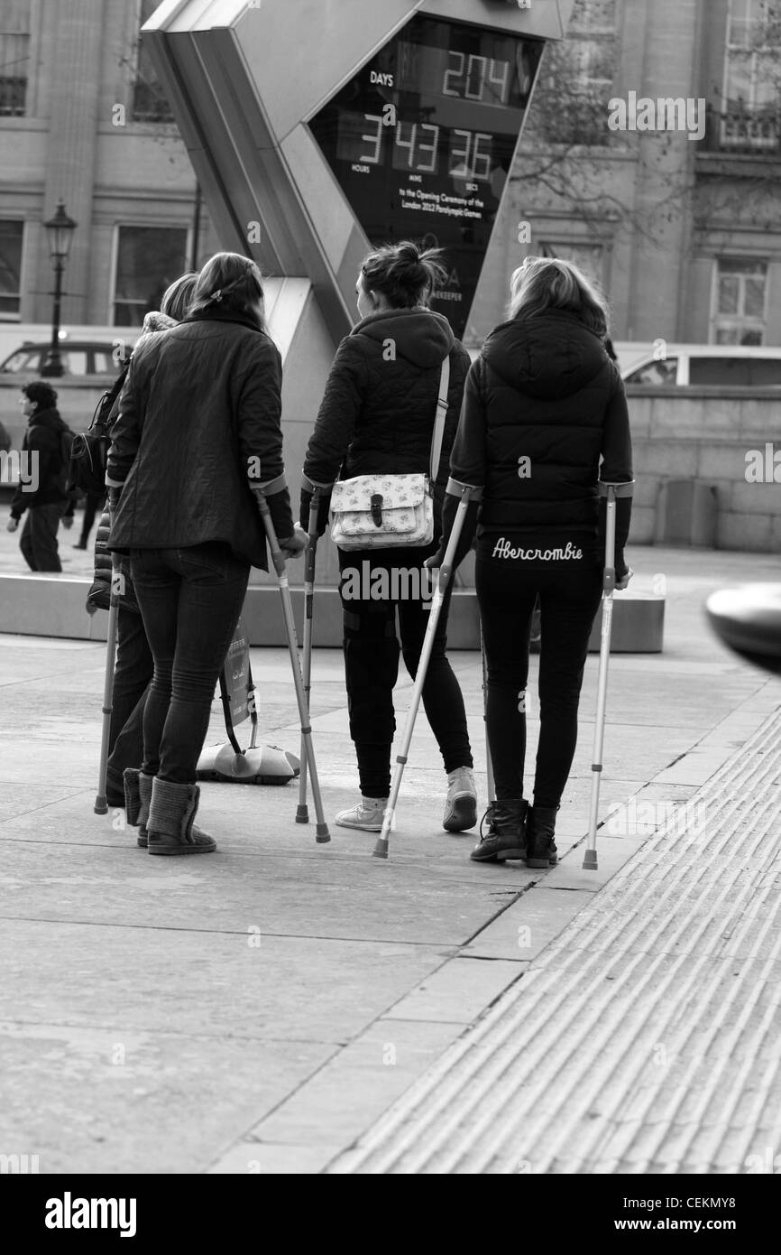 Three girls walking on crutches in Trafalgar Square, London Stock Photo
