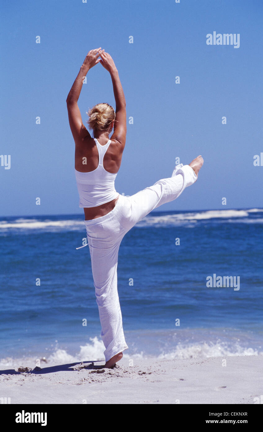 Female on beach kicking leg high up in air Stock Photo