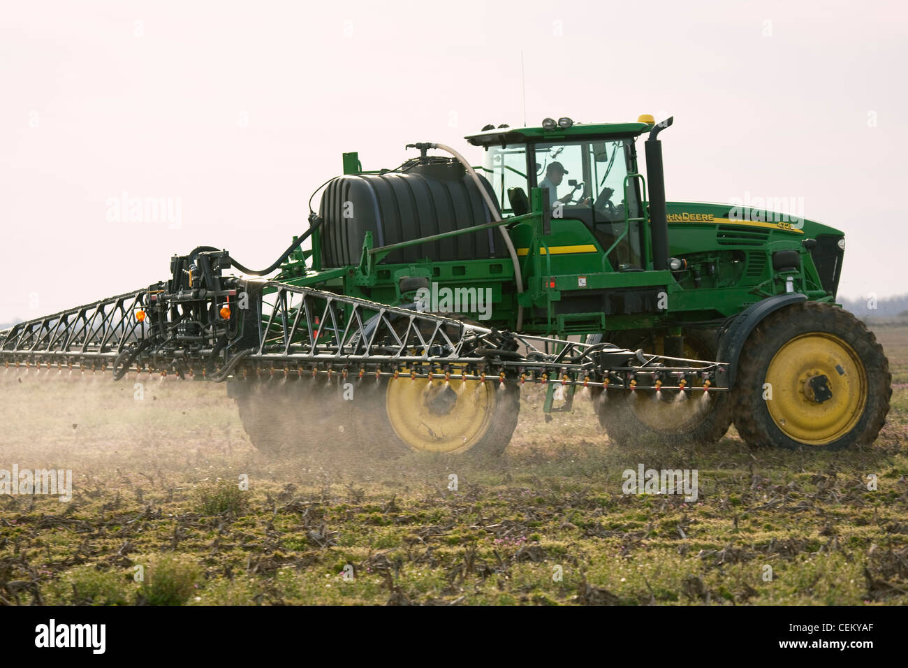 A John Deere sprayer applies pre-plant burndown herbicide in late Winter to a field that will be no-till planted to cotton. Stock Photo