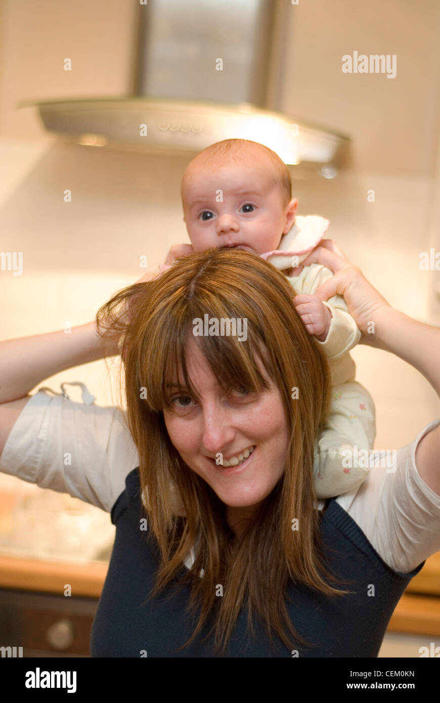 Female two month old baby being held on an adult female's shoulders Stock Photo