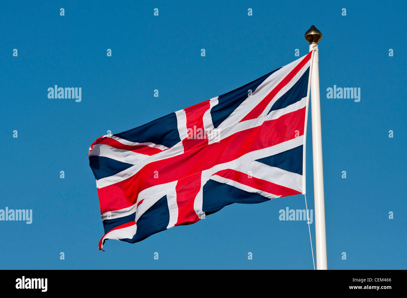A union jack flag flying against a clear bright blue sky. Stock Photo