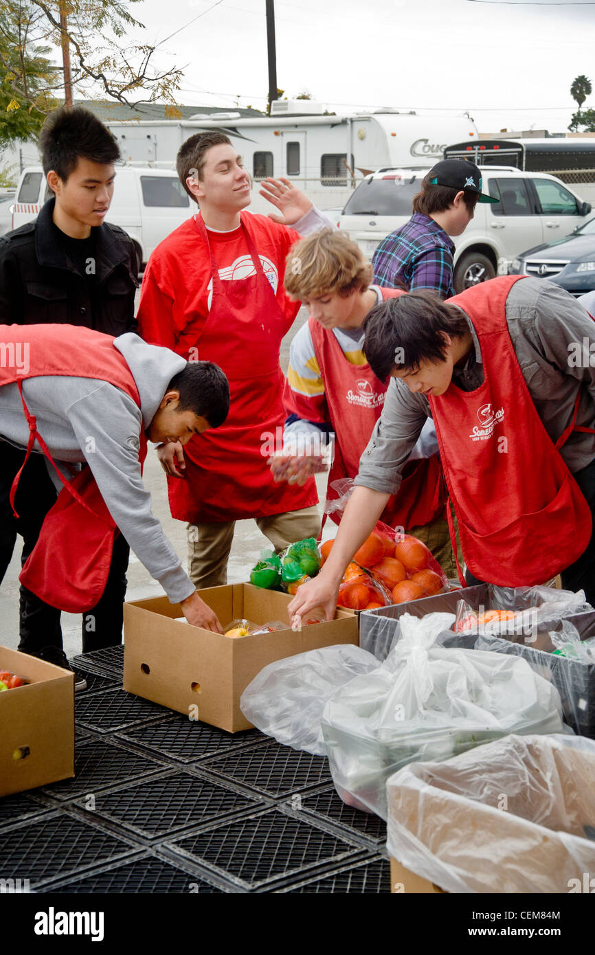Middle class charitable volunteers pitch in delivering food at a Costa Mesa, CA, soup kitchen to feed the homeless. Stock Photo