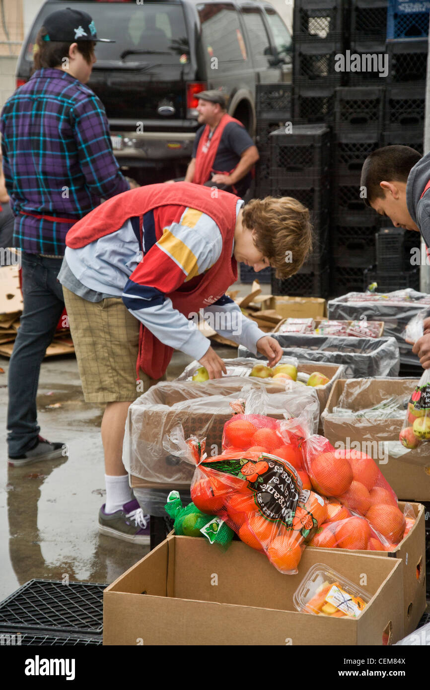 Middle class charitable volunteers pitch in delivering food at a Costa Mesa, CA, soup kitchen to feed the homeless. Stock Photo