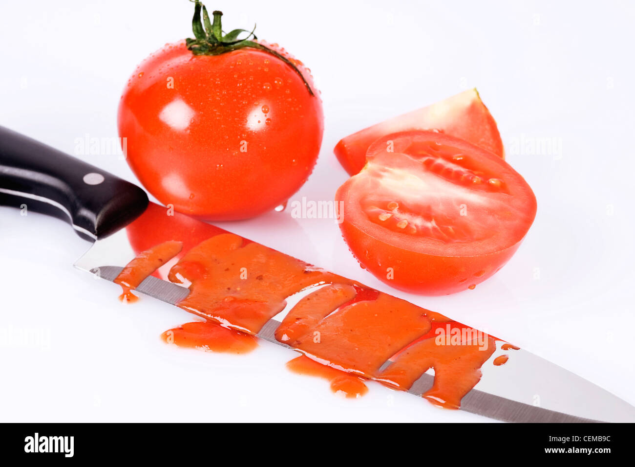 tomatoes and knife stained with ketchup over white Stock Photo