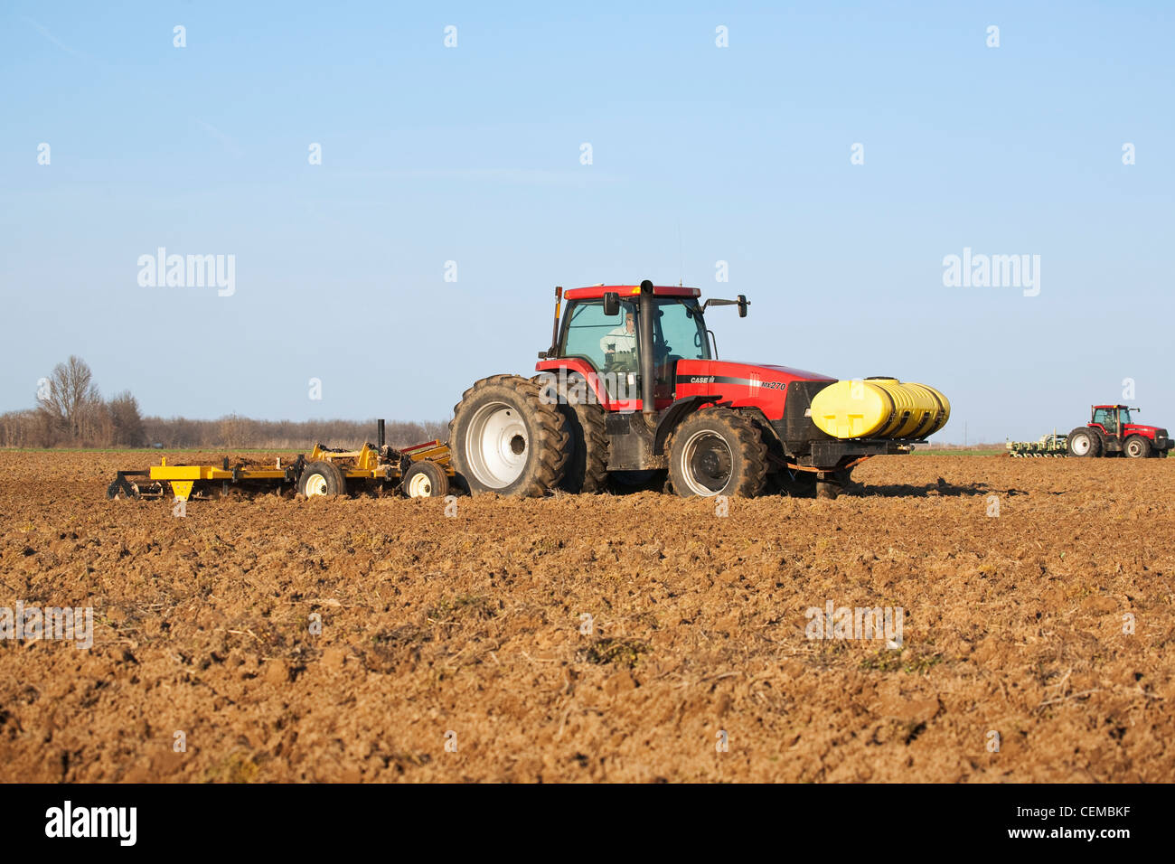 Two Case IH tractors and field implements finish soil preparation of a field in late Spring for the planting of cotton. Stock Photo