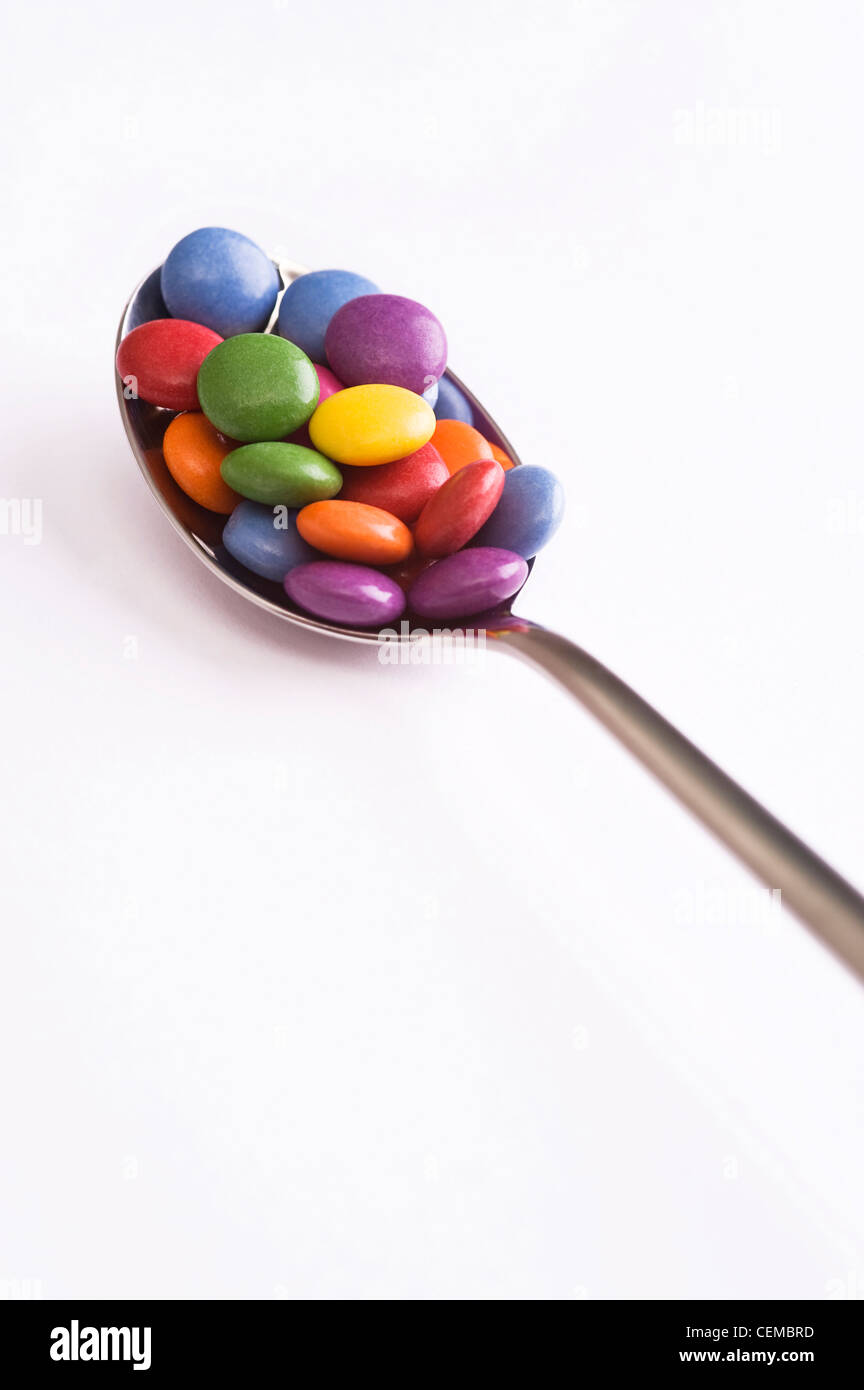 spoon with colorful sweets over white background Stock Photo