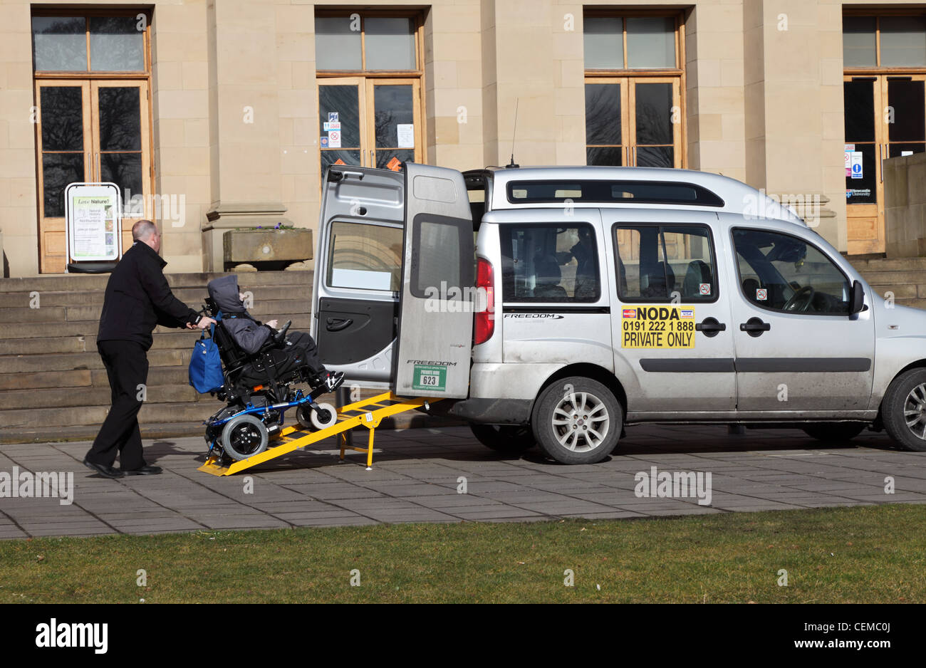 Taxi driver assisting passenger in wheelchair to leave using ramp. Newcastle north east England UK Stock Photo