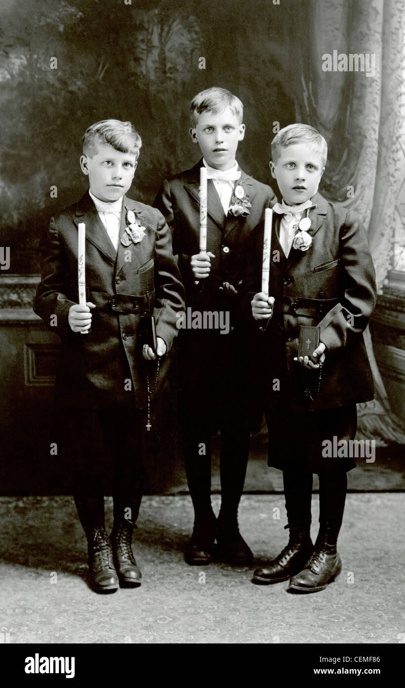 Early 1900s vintage photo of 3 young boys at their confirmation holding candles and bibles. Stock Photo