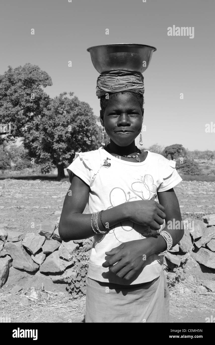 Malian Girl carrying her dishes to wash in the river, Djenné, Mali Stock Photo