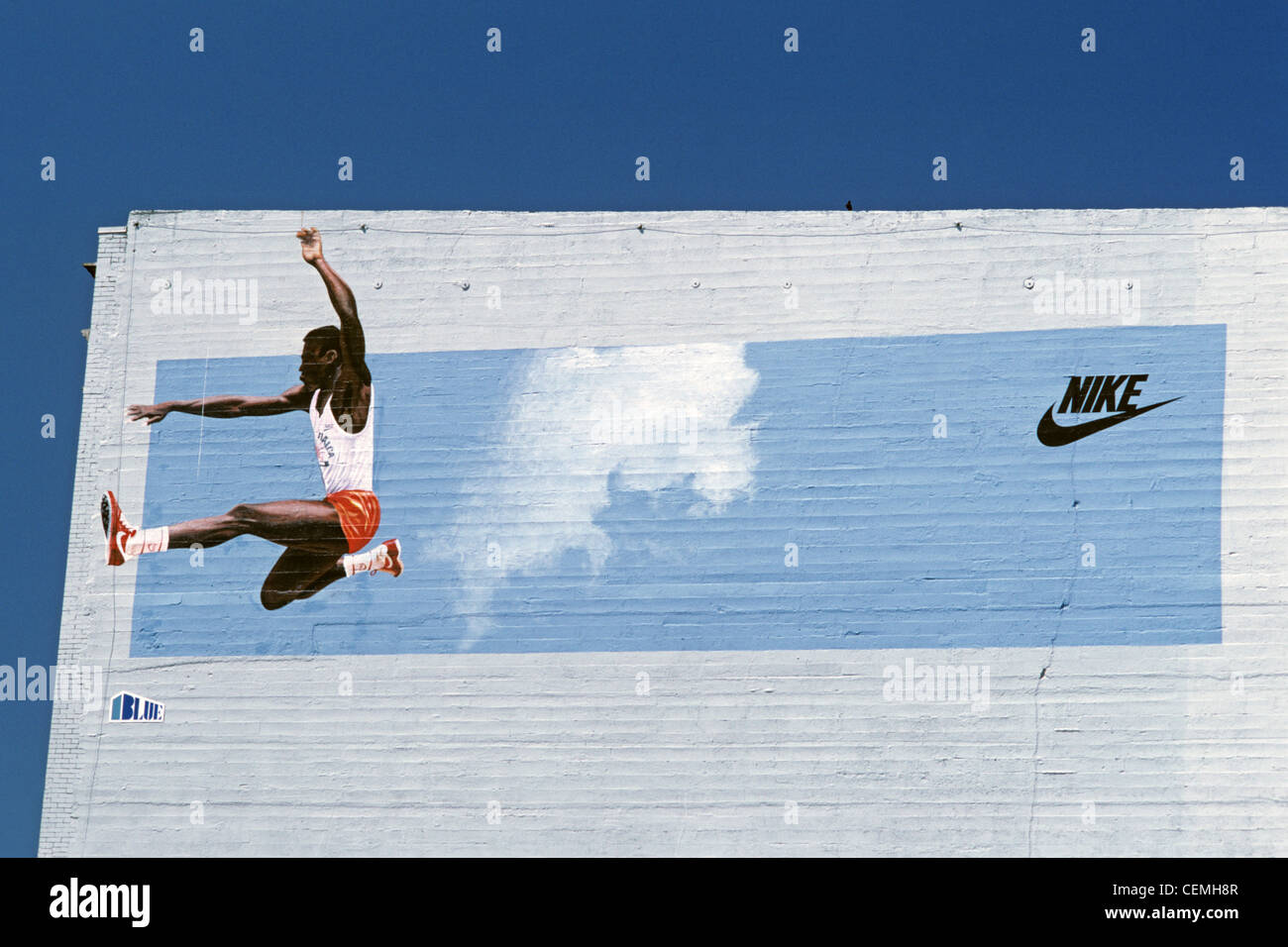 Retro image of Nike Ad Carl Lewis iconic athlete doing his long jump side  of building painted mural Stock Photo - Alamy