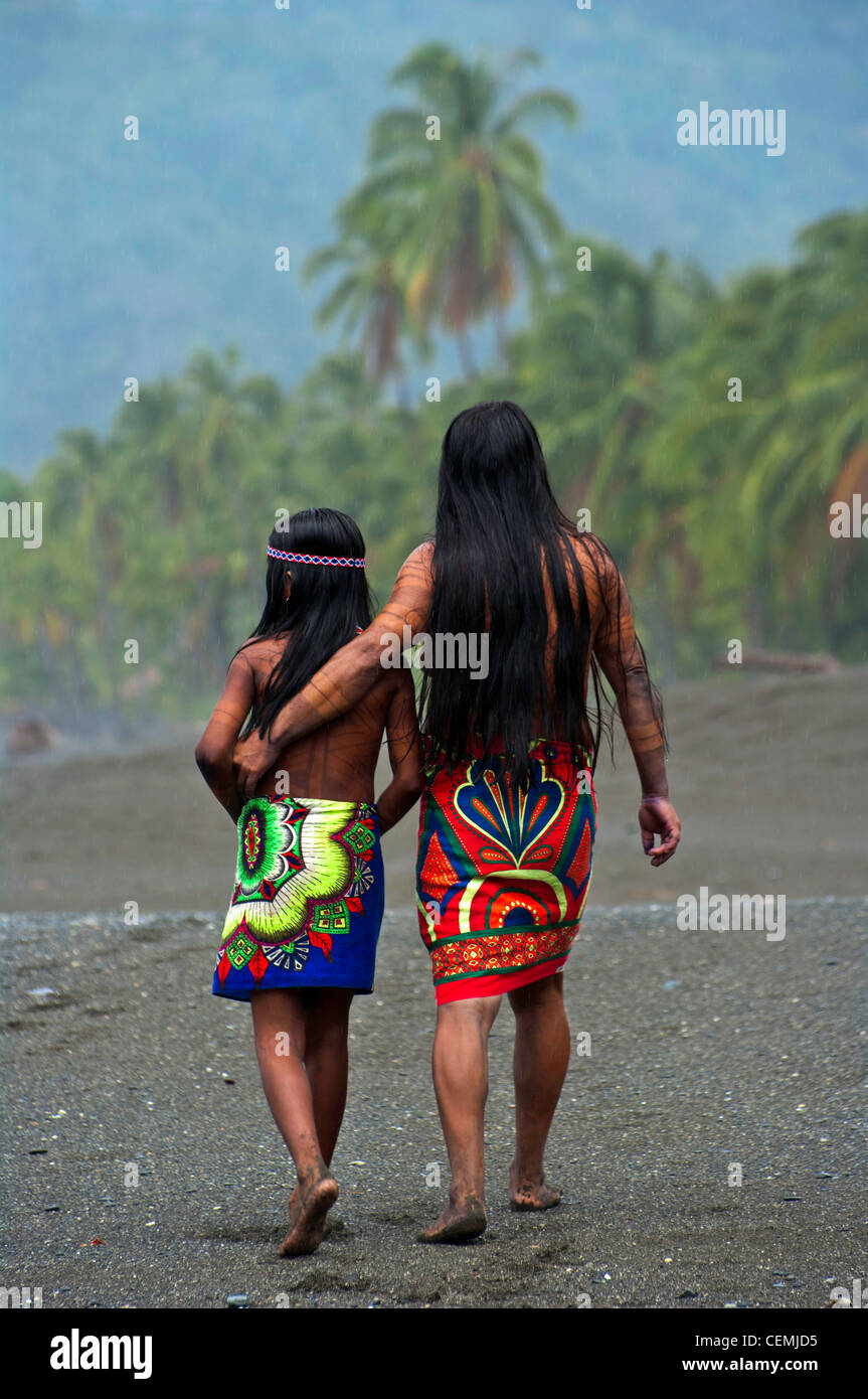 An Embera mother and daughter walk on the beach by their home in the Darien Jungle of Panama Stock Photo