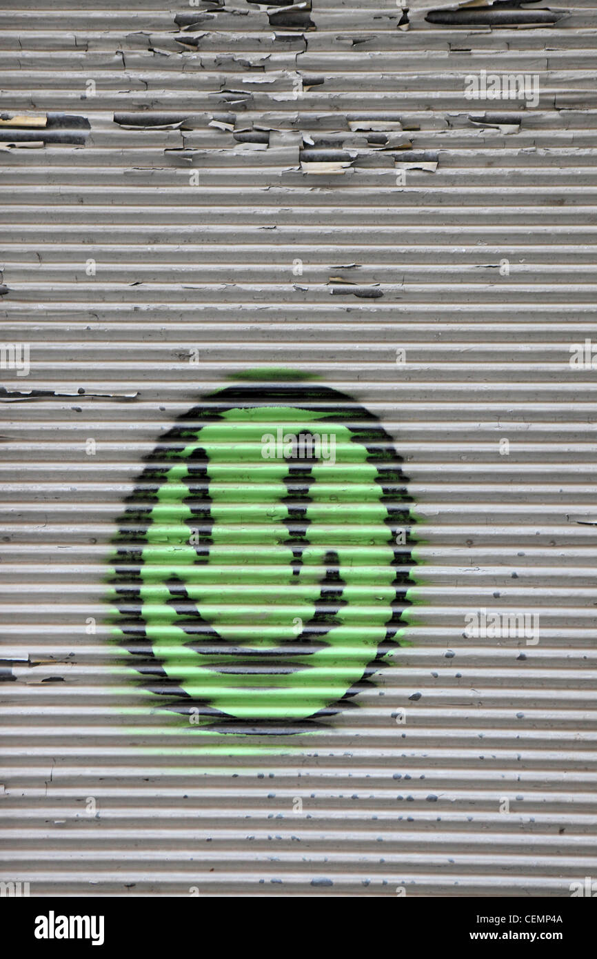 Green smiley face graffiti, spray painted in metal shutter, Lisbon, Portugal Stock Photo