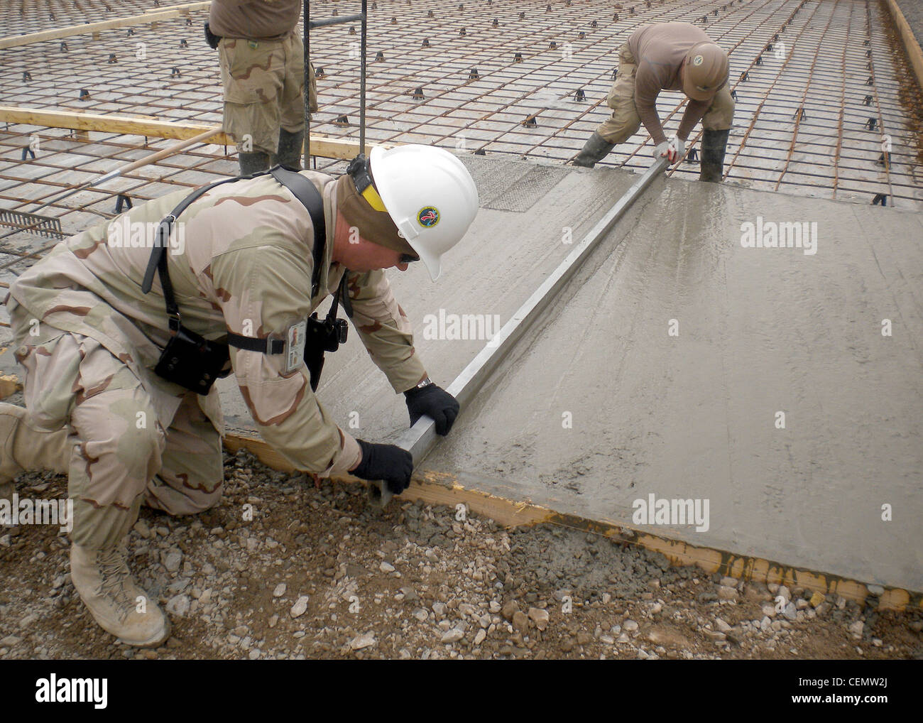 KANDAHAR PROVINCE, Afghanistan (Feb. 4, 2012) Senior Chief Builder Robert Morrison, left, and Builder 3rd Class Nathaniel Callaham, assigned to Detachment PASAB of Naval Mobile Construction Battalion (NMCB) 7, level concrete with a metal screed during the placement of concrete pads at Forward Operating Base PASAB. NMCB-7 and its detachments are one of two Seabee battalions supporting the International Security Assistance Force as part of Task Force Stethem in the U.S. Central Command area of responsibility Stock Photo